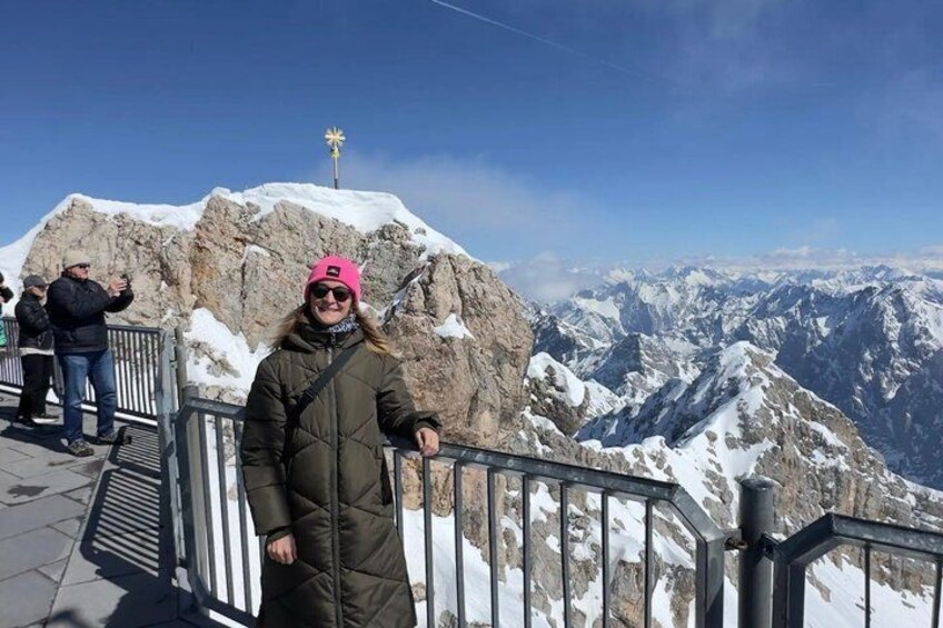 A person standing on a snow-covered mountain ridge with a clear sky and distant mountains in the background. 1