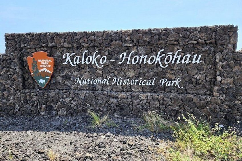 A stone wall with the text 'Kaloko - Honokahua National Historical Park' and a logo of the National Park Service. 1