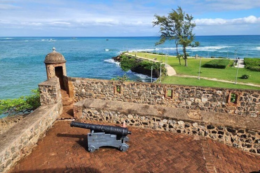 A coastal fort with a cannon, stone walls, and a view of the ocean. 3