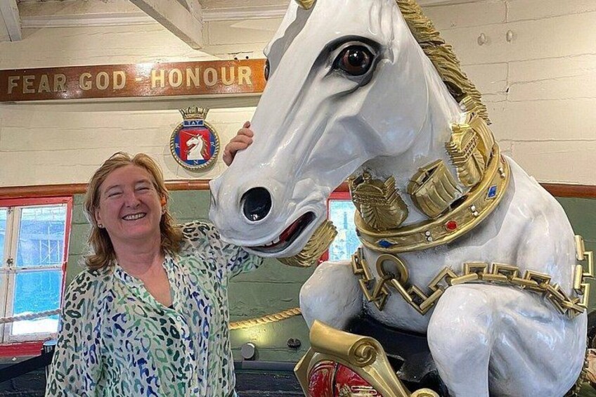 A woman standing next to a large, ornate horse statue. 4
