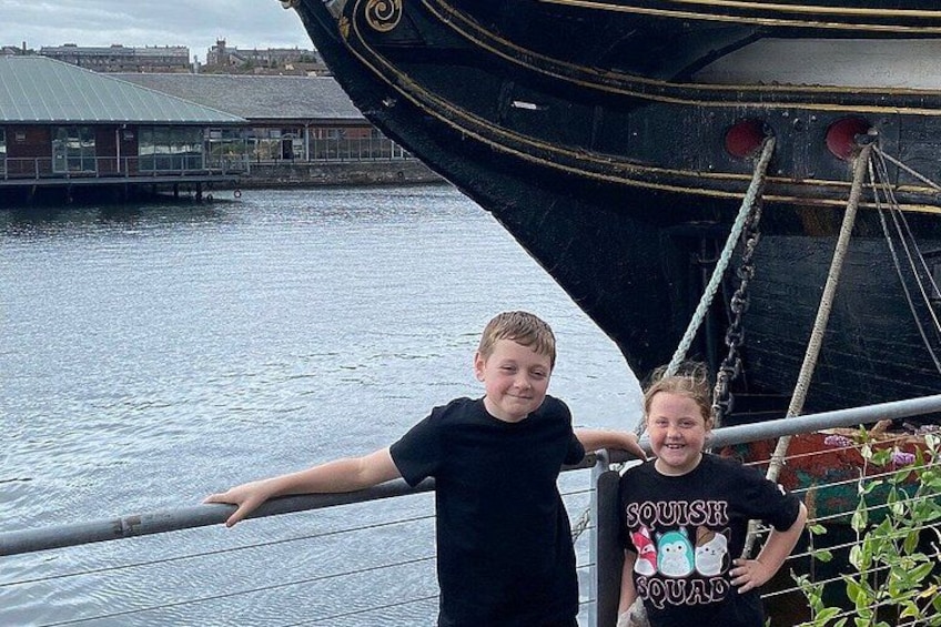Two people standing by a boat with a cityscape in the background. 5