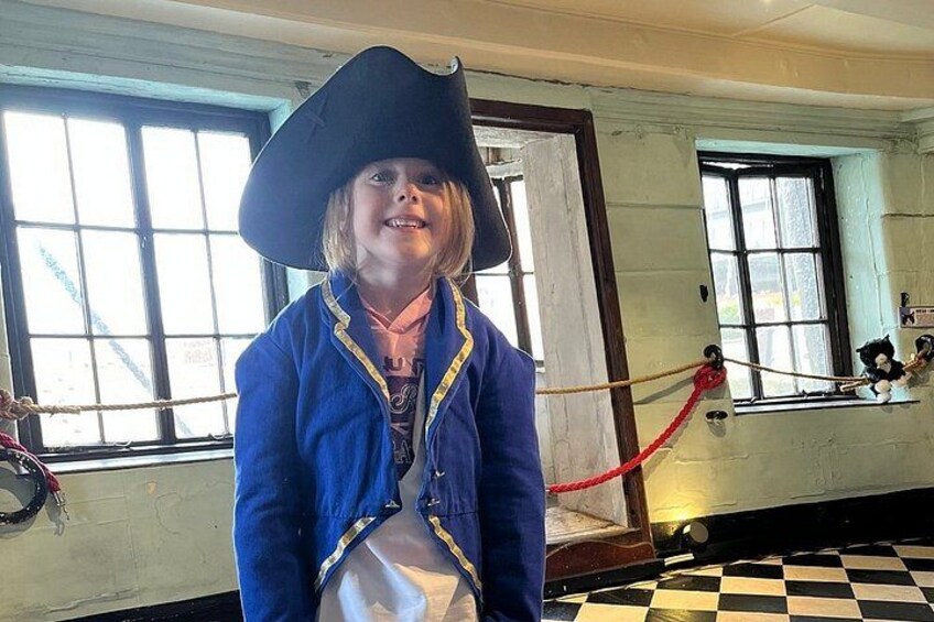 A person in a pirate costume with a large hat and a blue jacket with yellow trim. 5
