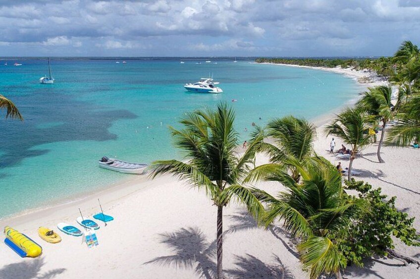 A beach with clear turquoise water, palm trees, and boats. 1