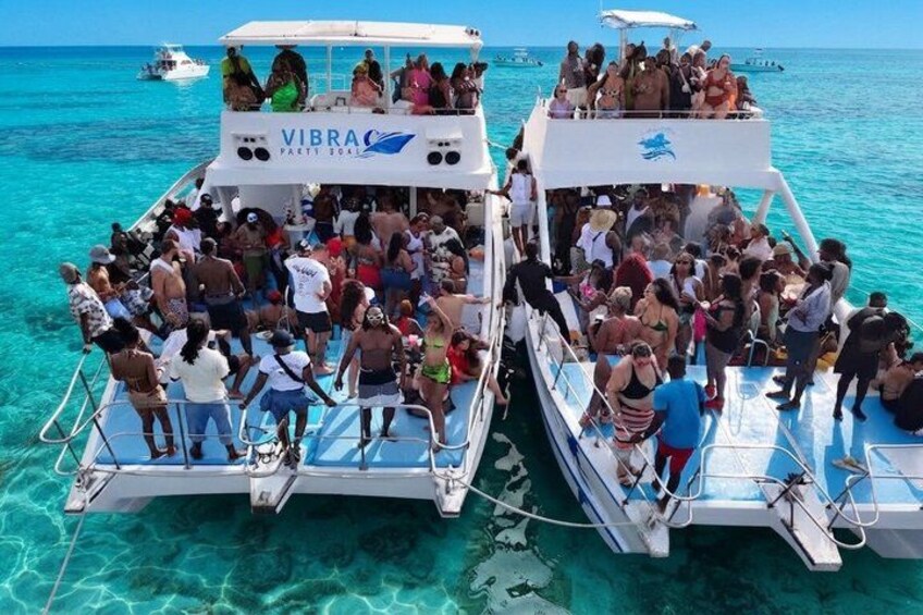 Two boats with people on them, floating on clear blue water. 4