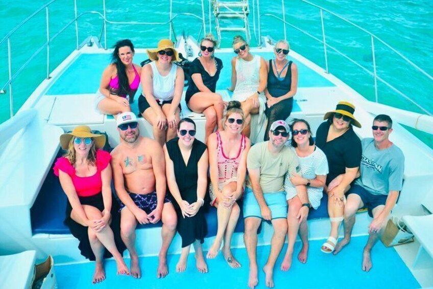 A group of people on a boat with a blue deck and clear turquoise water. 4