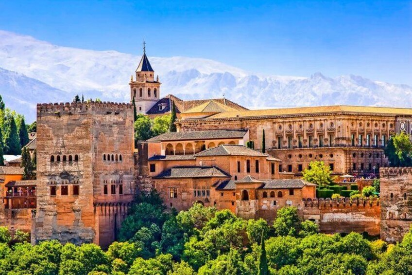 A historic building complex with a prominent tower and a large courtyard surrounded by trees. 1