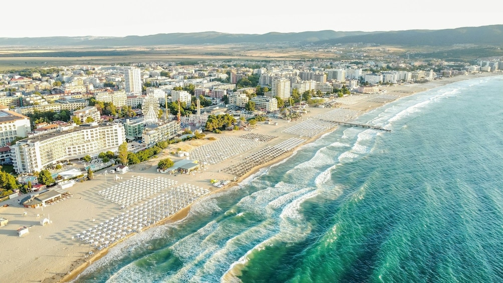 A coastal cityscape with a beach, hotels, and a Ferris wheel. 5