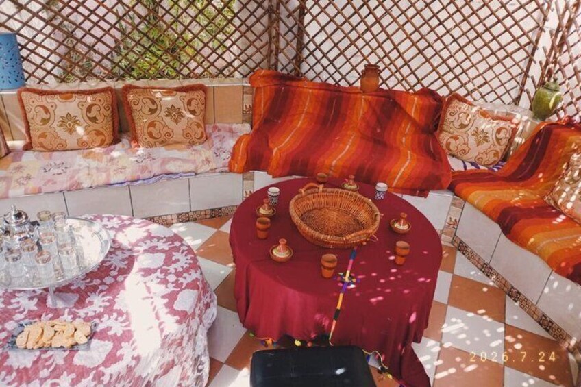 A traditional Moroccan setting with a patterned sofa, a round table with tea set, and a lattice backdrop. 1