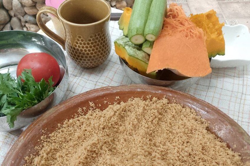 A table with a bowl of breadcrumbs, a metal bowl with a tomato and parsley, a mug, and a bowl of sliced vegetables. 3