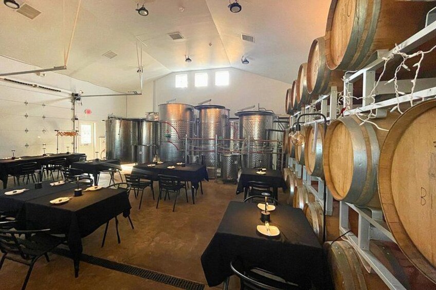 A wine cellar with wooden barrels and stainless steel tanks. 3