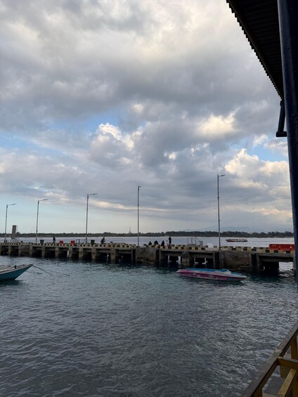 A pier with boats, a cloudy sky, and a distant shoreline. 3