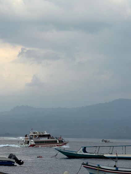 A ferry boat named 'SEMAYAONE PRIDE 99' with passengers, docked at a harbor with calm waters and distant mountains. 5