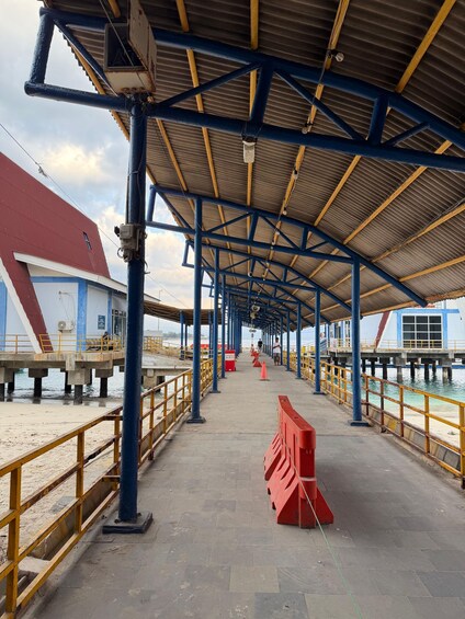 A covered walkway with blue and yellow railings, leading to a pier extending into the water. 4