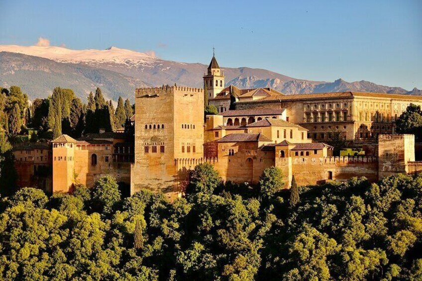 A historic castle with a prominent tower, surrounded by lush greenery and mountains in the background. 2