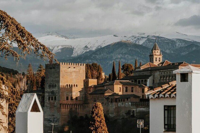 A medieval castle, a church, and snow-capped mountains in the background. 5