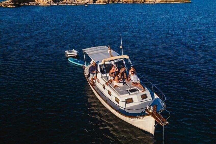 A boat with people on it, a smaller boat nearby, and calm water. 2