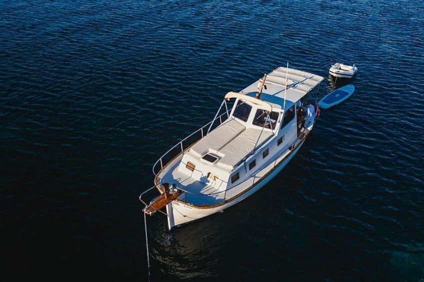 A white motorboat with a cabin and a small outboard motor on the back, floating on calm water. 5