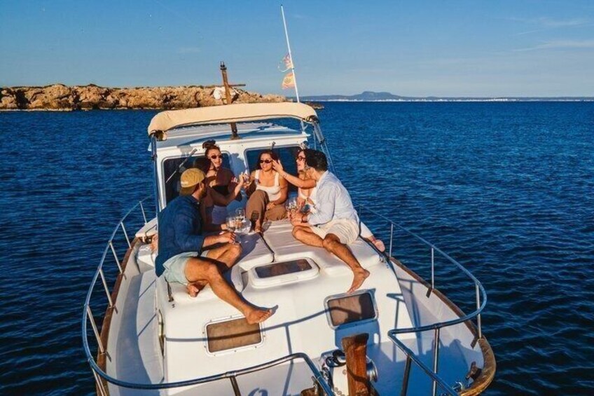A boat with people sitting on the deck, a rocky shoreline in the background, and calm water. 5