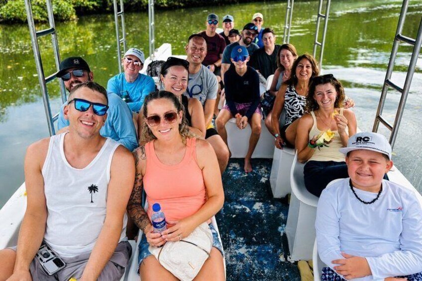 A group of people on a boat with water and greenery in the background. 2
