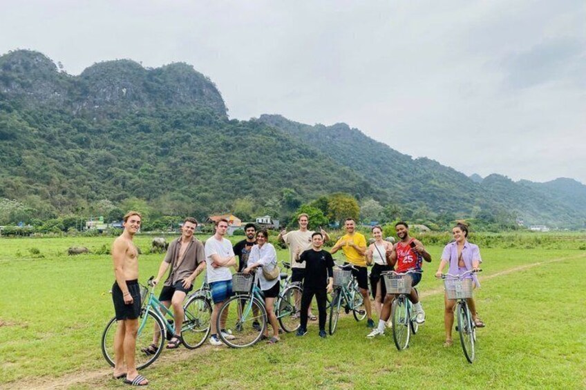 A group of people on bicycles in a grassy field with mountains in the background. 2