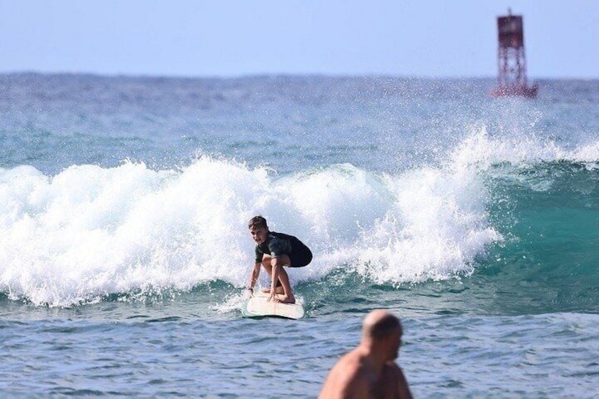 A person surfing a wave with a lighthouse in the background. 3