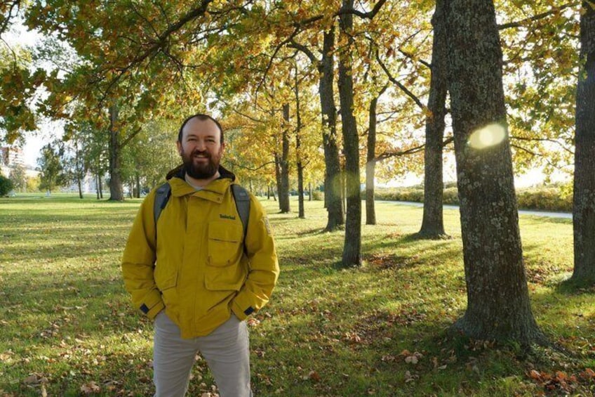 A person standing in a park with trees and grass. 2