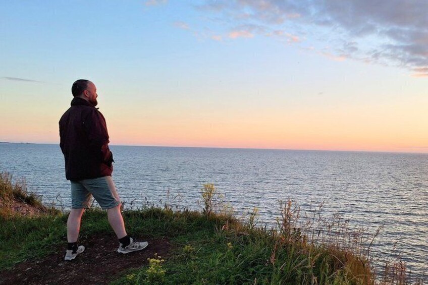 A person standing by a body of water during sunset. 3
