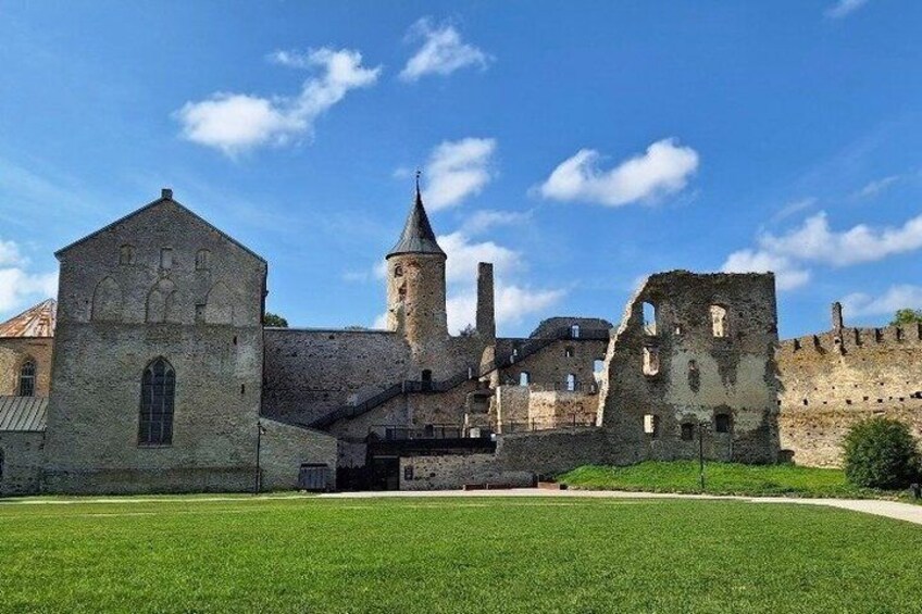 A historic stone building with a tower, surrounded by a well-maintained lawn and a stone wall. 1