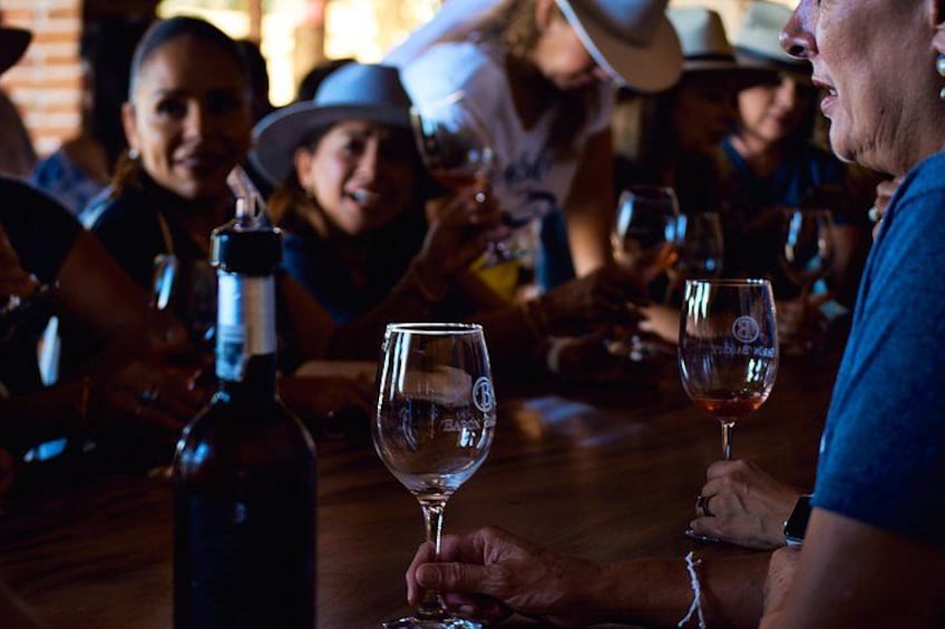 A group of people sitting at a table with wine glasses and a bottle of wine. 5