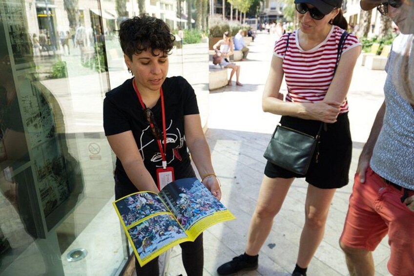 A person reading a magazine, another person standing nearby, and a glass display case with a map. 4