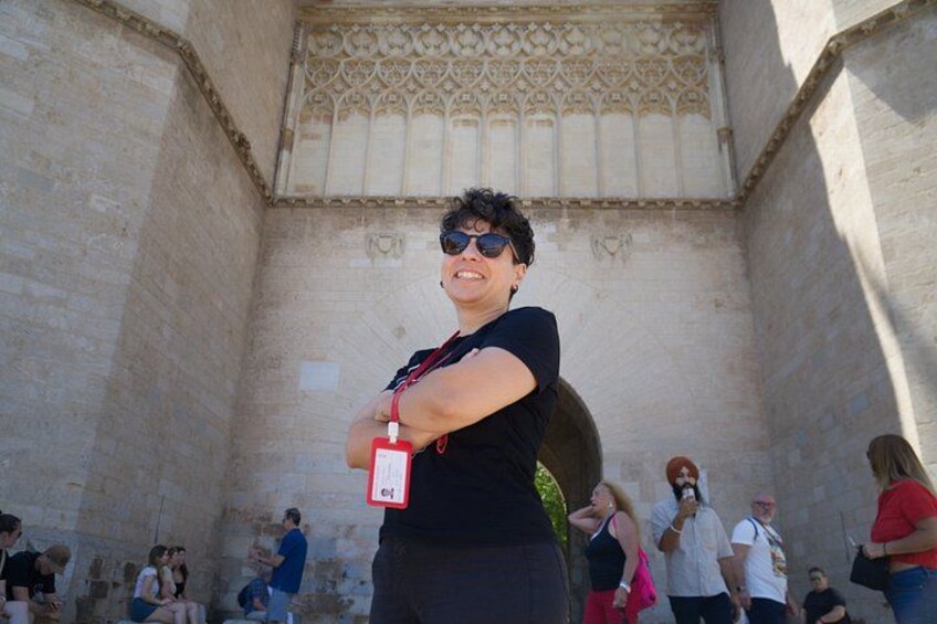 A person standing in front of a stone wall with a decorative pattern at the top. 3
