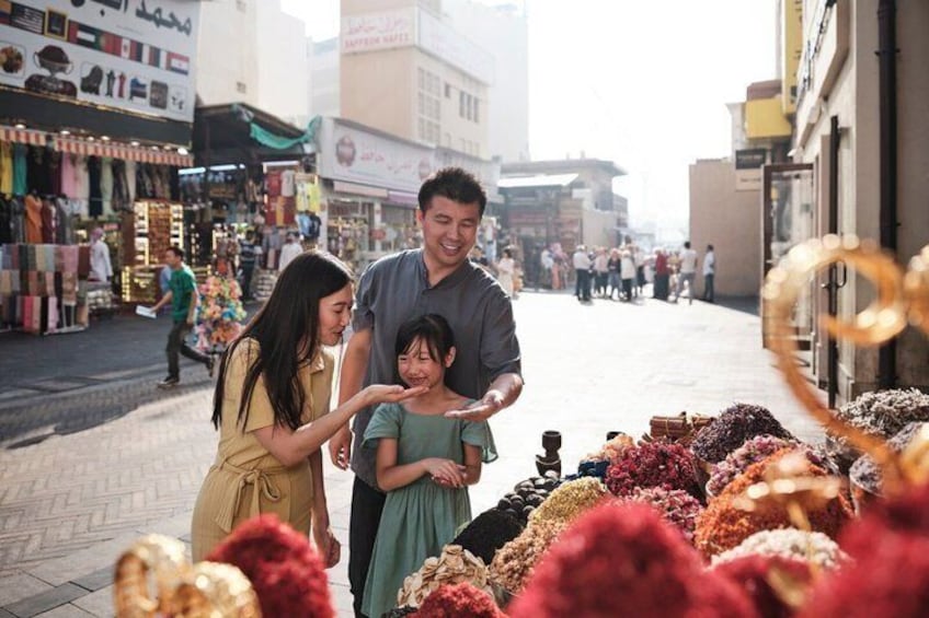 A family shopping in a market with various stalls and people in the background. 5