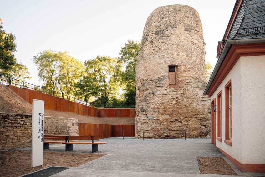 A stone tower, a wooden bench, and a building with red doors. 2