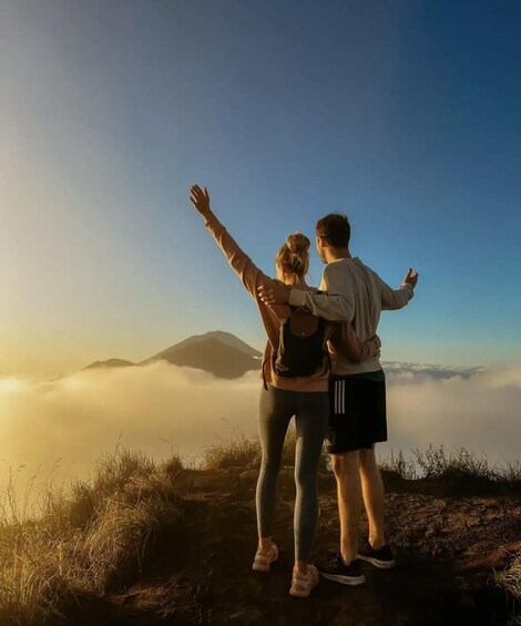 A couple embracing on a mountain peak with a sunrise in the background. 1