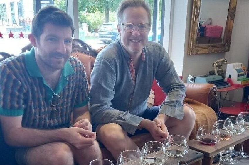 Two people sitting on a couch with wine glasses in front of them. 3