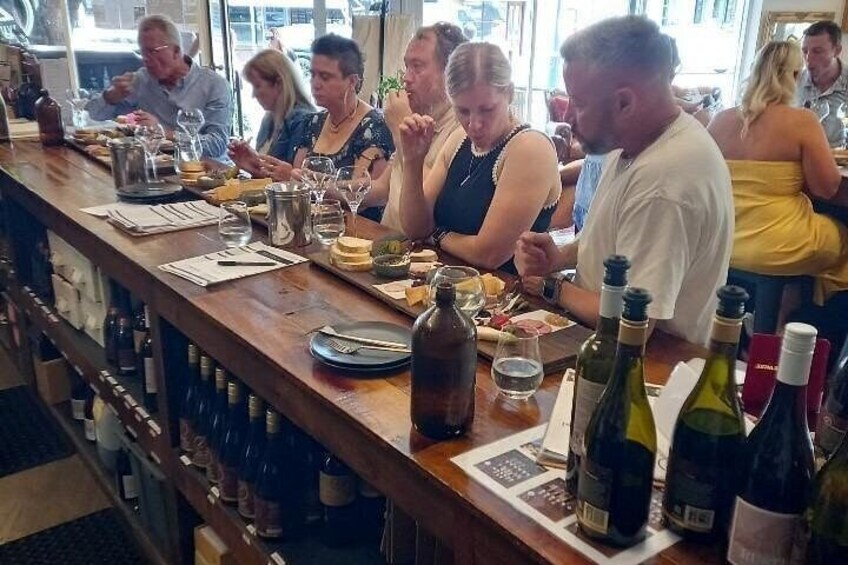 A bar with people dining, bottles of wine, and glasses on the counter. 4