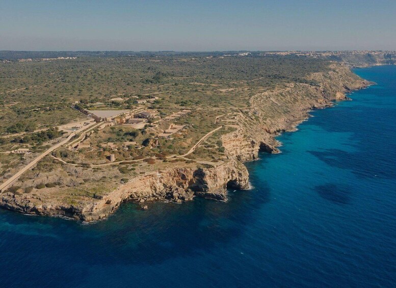 An aerial view of a coastal landscape with rocky cliffs, a winding road, and scattered buildings. 5