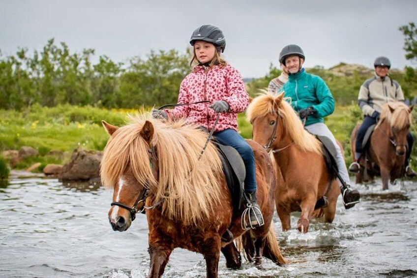 Three people riding horses along a river. 4