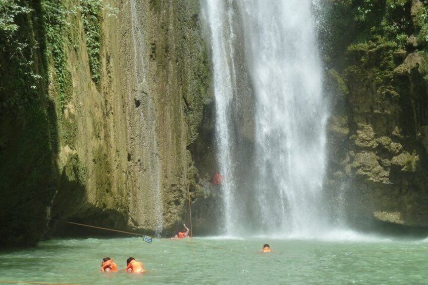 A waterfall, water, and people swimming. 2