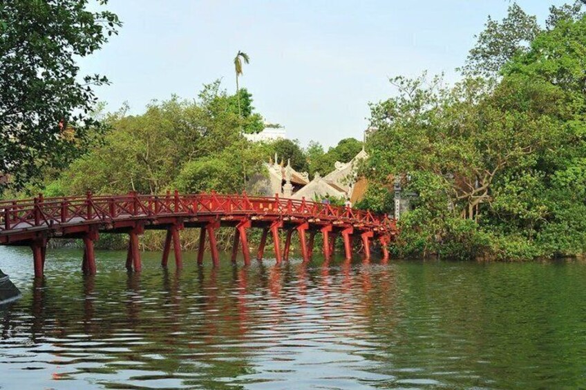 A red bridge over water with trees and a building in the background. 2