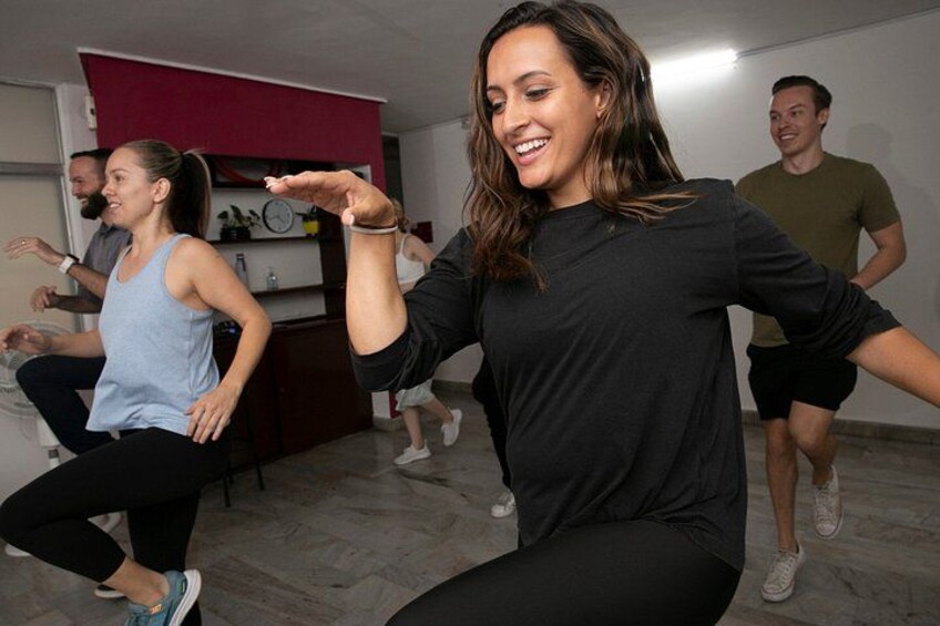 A group of people exercising in a room with a red wall and a clock. 3