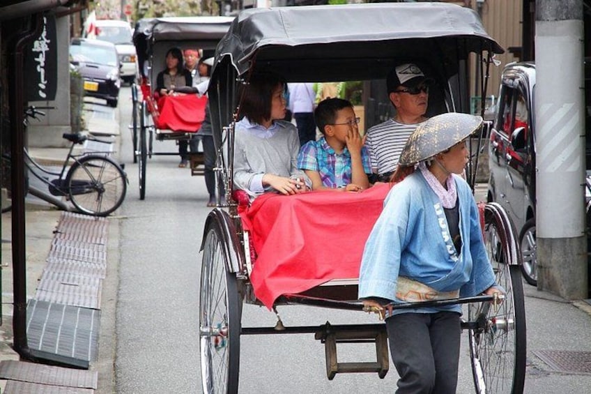 En traditionell rickshaw med passagerare, en cykel och en fotgängare på en stadsgata. 2