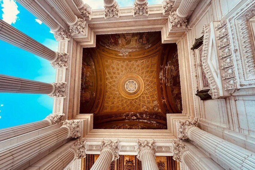 Un intérieur architectural richement décoré, avec un plafond travaillé et des colonnes de style classique. 4