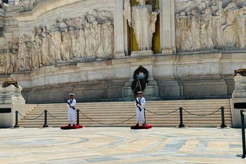 Deux gardes se tiennent devant un imposant bâtiment orné de sculptures complexes. 2