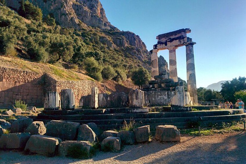 Ancient ruins with columns and a stone archway, surrounded by rocks and a mountainous backdrop. 4
