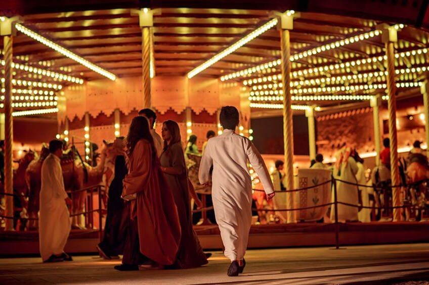 A covered outdoor area with people walking and standing, illuminated by string lights. 3