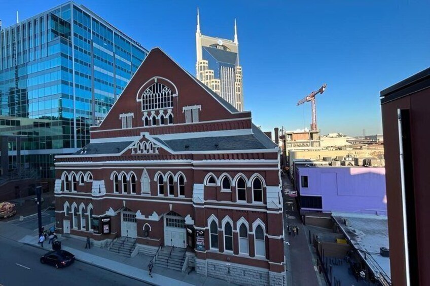 A historic building with arched windows and a central tower, surrounded by modern high-rise buildings. 3