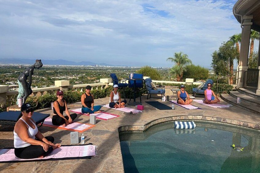A group of people doing yoga on mats by a pool with a scenic view. 2