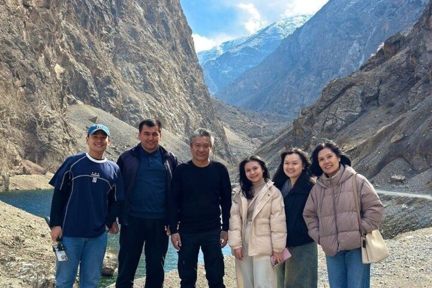 A group of people standing in a mountainous area with rocky terrain and a river. 4