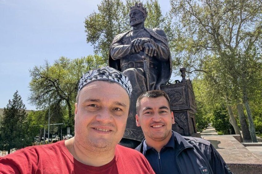 Two people in front of a statue with a crown and a pedestal. 2
